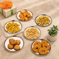 Assorted snacks on plates with a decorative gift and plant on a beige surface