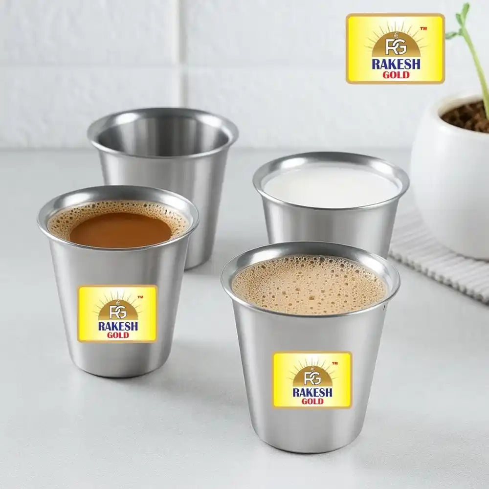 Four metal cups with Rakesh Gold coffee on a white surface